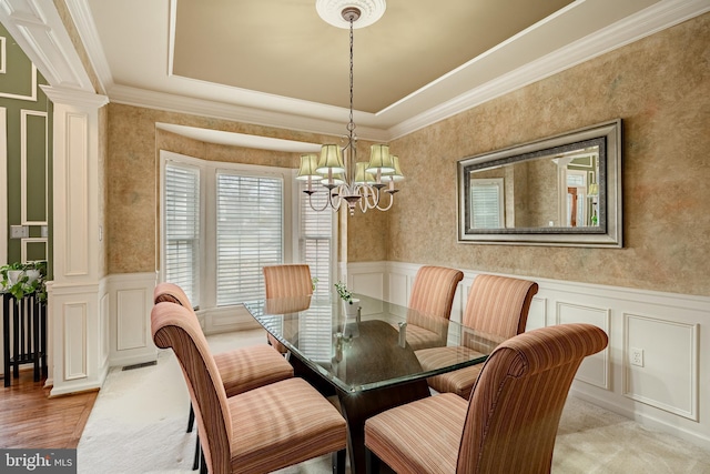 dining area with a notable chandelier, wainscoting, a decorative wall, and decorative columns