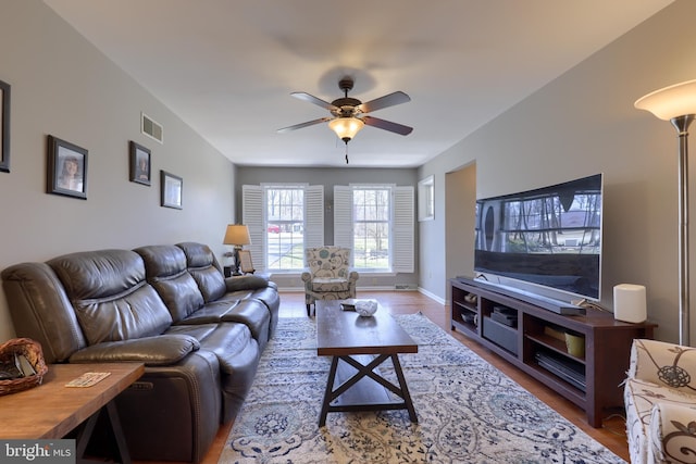 living room with wood finished floors, visible vents, baseboards, and ceiling fan