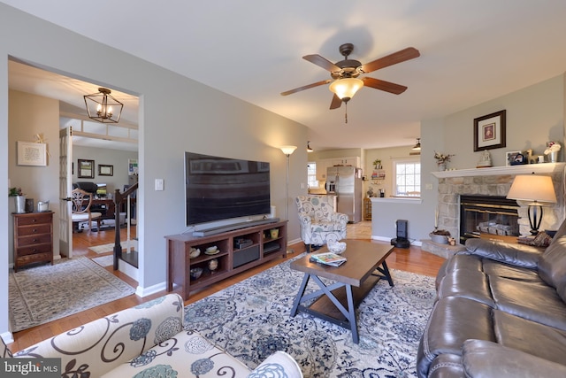 living room featuring a fireplace, wood finished floors, baseboards, and a ceiling fan