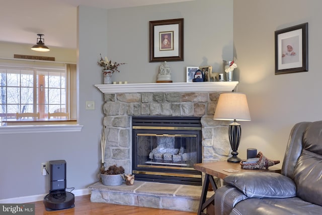 living area with wood finished floors, a fireplace, and baseboards