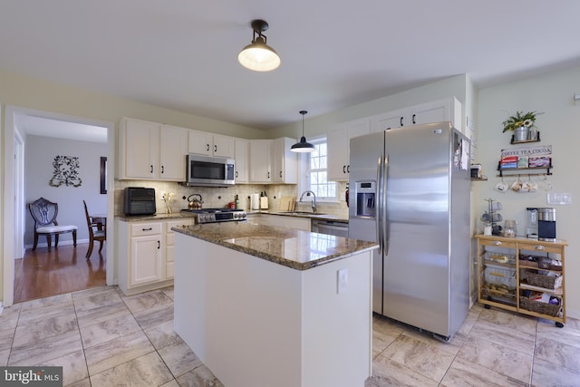 kitchen featuring marble finish floor, a kitchen island, stainless steel appliances, dark stone counters, and white cabinets