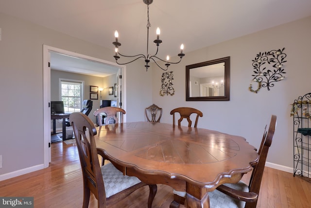 dining space featuring light wood-style floors, baseboards, and a chandelier