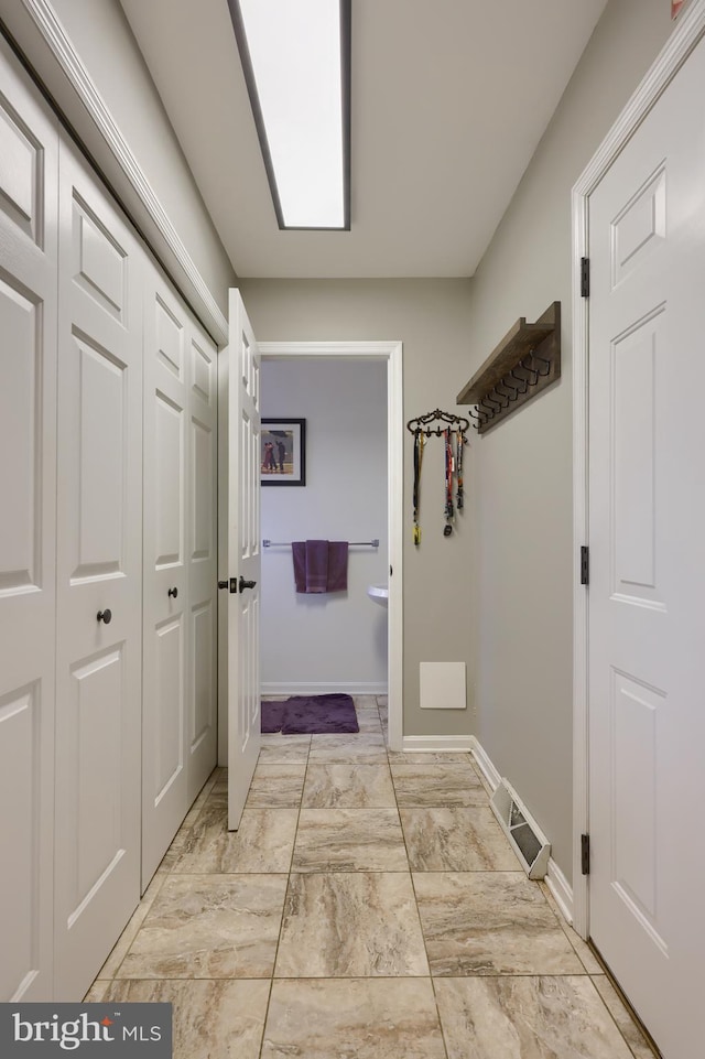 hall with marble finish floor and baseboards