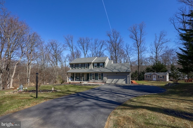 colonial house featuring a porch, a front lawn, a garage, and aphalt driveway