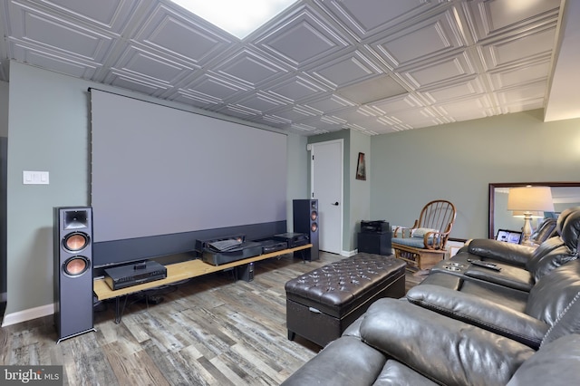 home theater featuring baseboards, an ornate ceiling, and wood finished floors