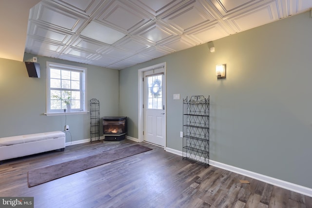 foyer entrance with baseboards, an ornate ceiling, a healthy amount of sunlight, and a wood stove