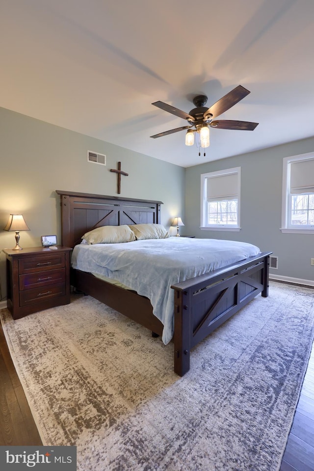 bedroom with visible vents, a ceiling fan, baseboards, and wood finished floors