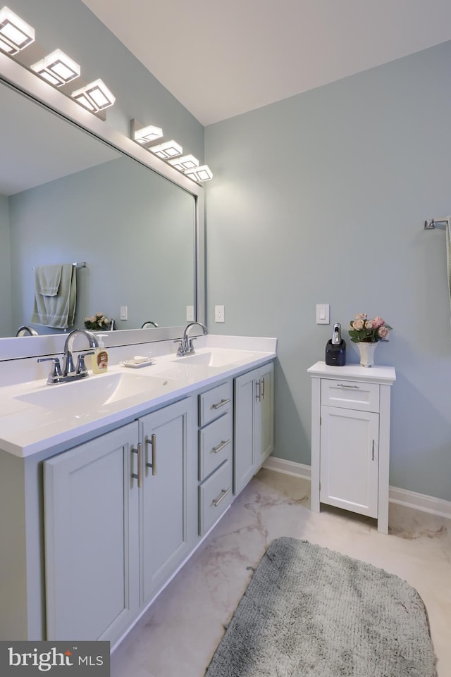 bathroom with double vanity, marble finish floor, baseboards, and a sink