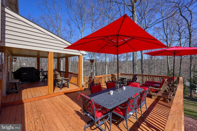 wooden terrace featuring a grill and outdoor dining space