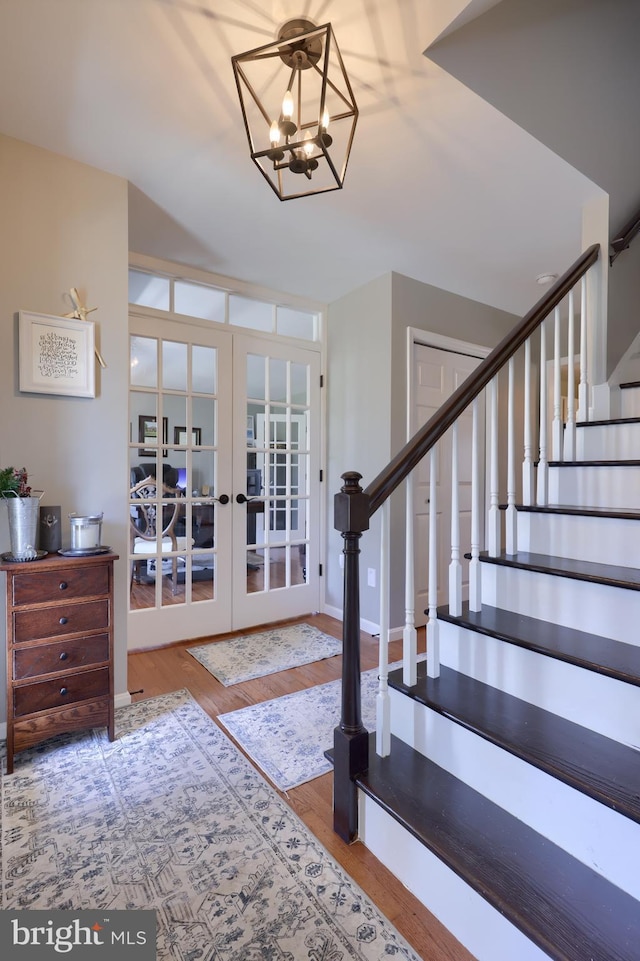 foyer entrance featuring a chandelier, french doors, stairs, and wood finished floors