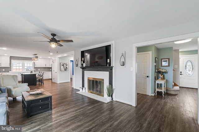 living room featuring a brick fireplace, recessed lighting, baseboards, and dark wood-style flooring