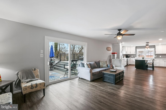 living area with a ceiling fan and dark wood-style flooring