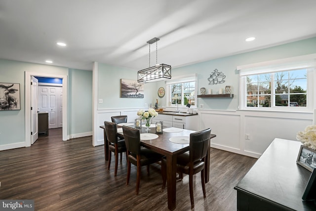 dining room featuring dark wood finished floors, a decorative wall, recessed lighting, and a wainscoted wall