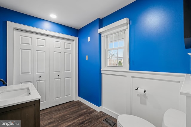 bathroom with vanity, toilet, wood finished floors, and visible vents