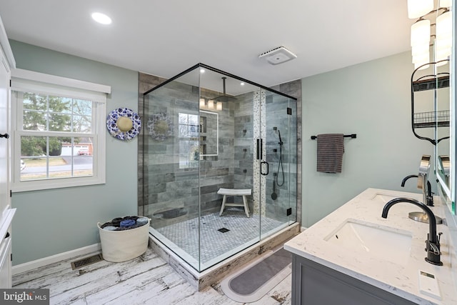 bathroom featuring double vanity, visible vents, a stall shower, and a sink