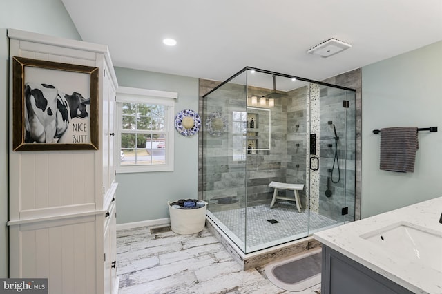 full bath featuring vanity, a shower stall, and baseboards