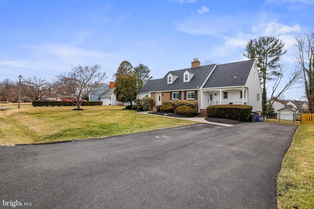 view of front of house with a front yard, fence, driveway, a porch, and a chimney