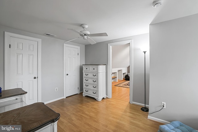 home office featuring a ceiling fan, light wood-style floors, visible vents, and baseboards