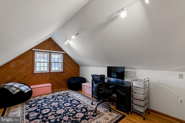 home office with wooden walls, baseboards, lofted ceiling, rail lighting, and wood finished floors