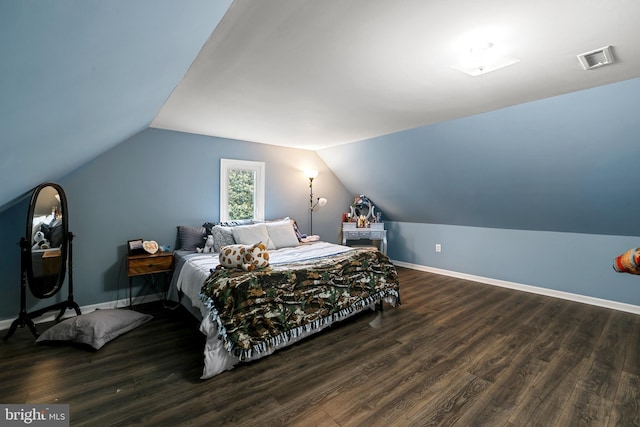 bedroom with visible vents, baseboards, lofted ceiling, and wood finished floors