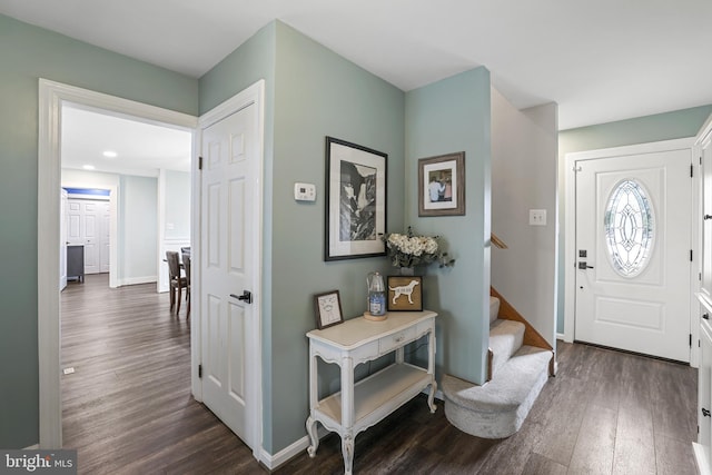 foyer entrance featuring baseboards, dark wood-style floors, and stairs