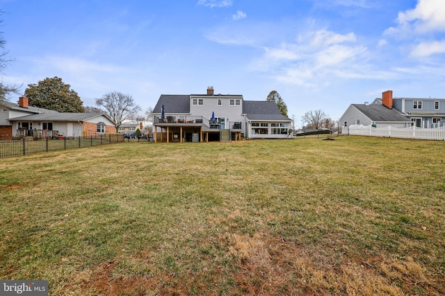 rear view of property featuring a deck, a yard, a fenced backyard, and a chimney