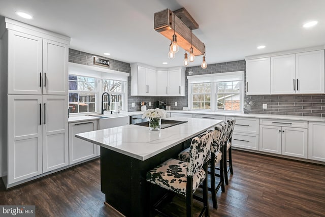 kitchen featuring a sink, a kitchen breakfast bar, white cabinets, and dark wood-style flooring