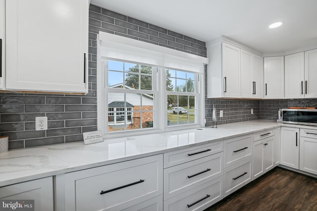 kitchen with stainless steel microwave, white cabinets, and decorative backsplash