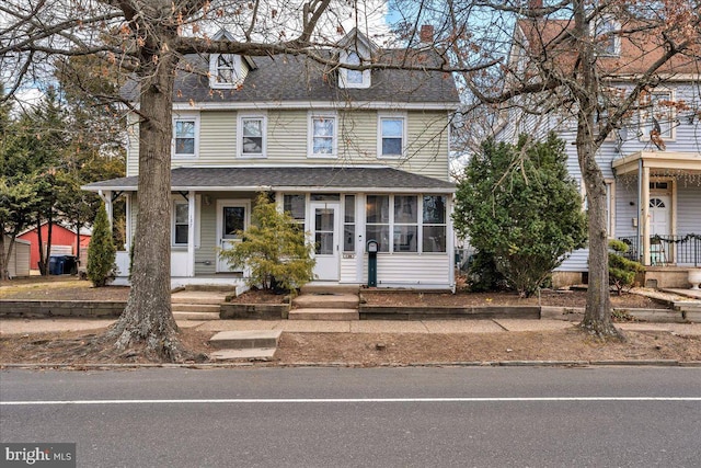 view of front of home featuring roof with shingles and a sunroom