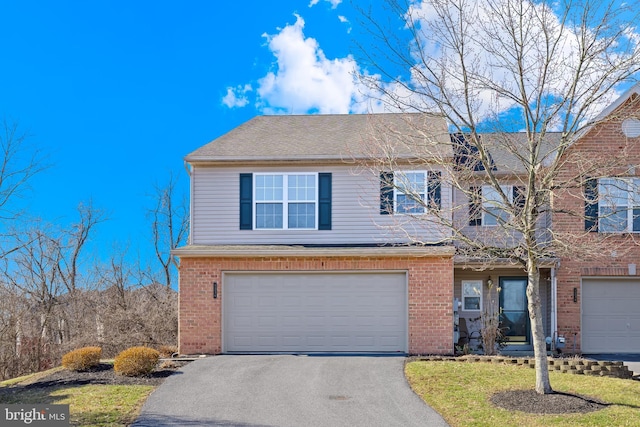 traditional-style house with an attached garage, brick siding, driveway, and a shingled roof