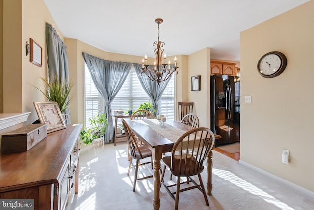 dining area featuring a notable chandelier, baseboards, and light carpet