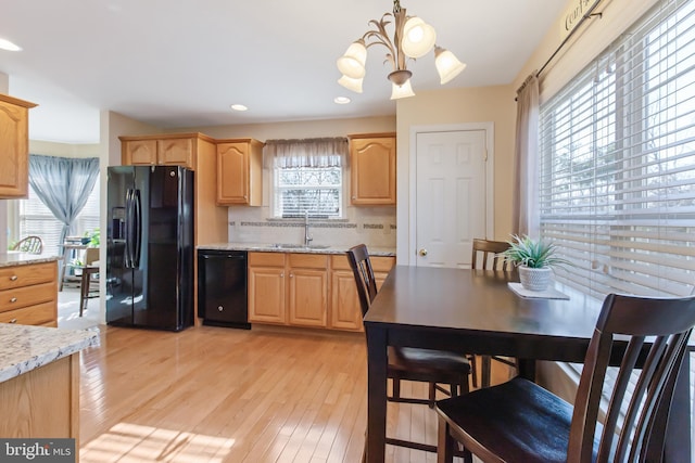 kitchen featuring light brown cabinets, decorative backsplash, light wood-style floors, black appliances, and a sink