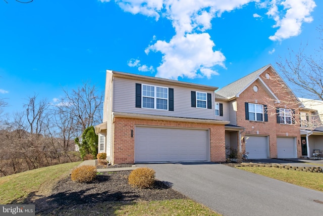 view of front of home with brick siding, an attached garage, and driveway