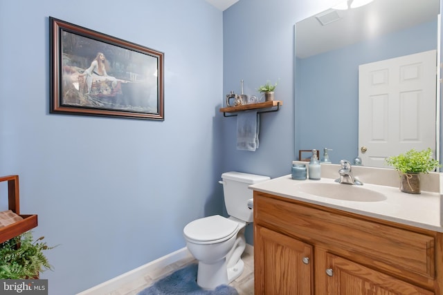 half bathroom with vanity, toilet, baseboards, and visible vents