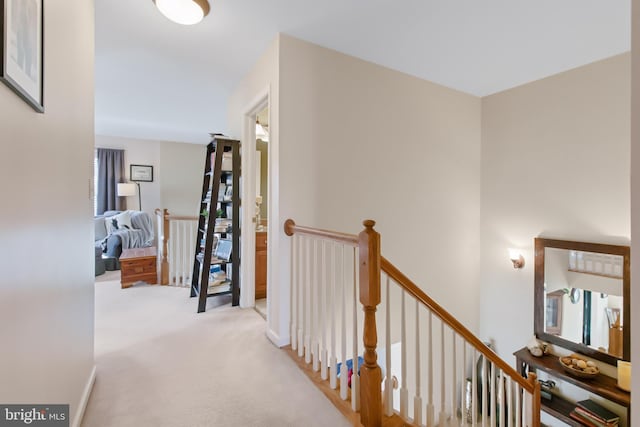 corridor with carpet flooring and an upstairs landing