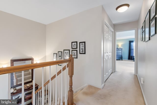 hall featuring baseboards, an upstairs landing, and light colored carpet