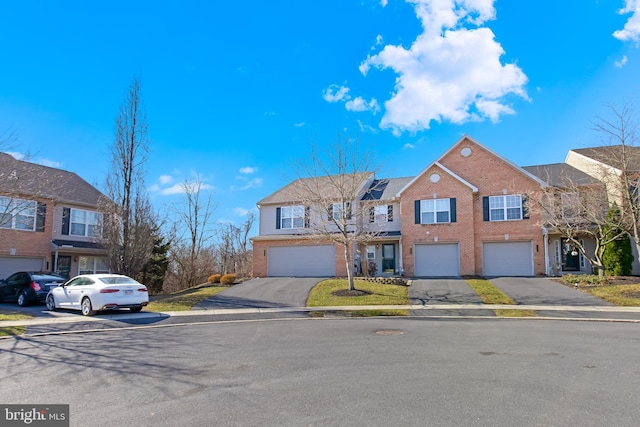 multi unit property featuring brick siding, driveway, and an attached garage