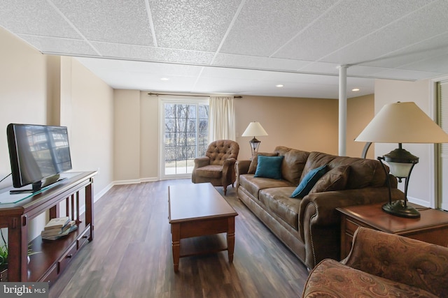 living room featuring a drop ceiling, baseboards, and wood finished floors