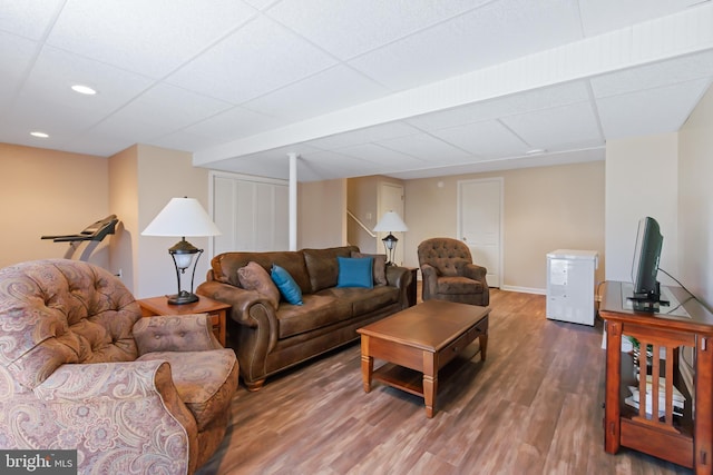 living room featuring baseboards, a drop ceiling, stairs, recessed lighting, and wood finished floors