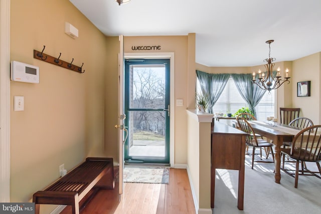 foyer entrance featuring a wealth of natural light, baseboards, a notable chandelier, and wood finished floors