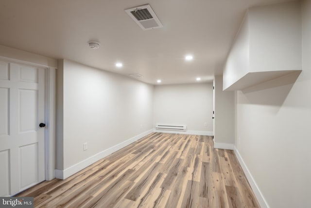 finished basement with baseboards, visible vents, light wood finished floors, a baseboard radiator, and recessed lighting