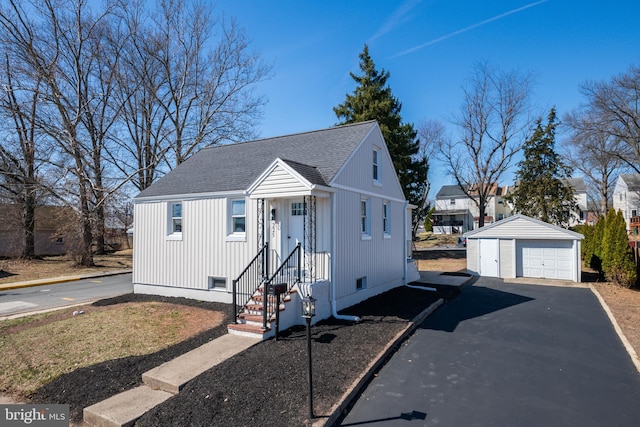 view of front of house with an outbuilding, driveway, a shingled roof, and a detached garage