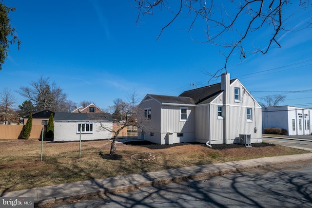 view of property exterior featuring cooling unit, fence, a chimney, crawl space, and a lawn