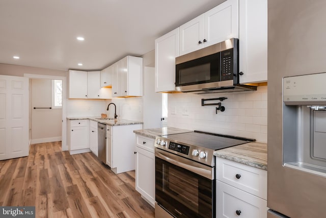 kitchen with appliances with stainless steel finishes, white cabinetry, and a sink