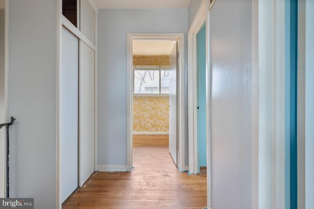 hallway with baseboards, light wood-style flooring, and wallpapered walls