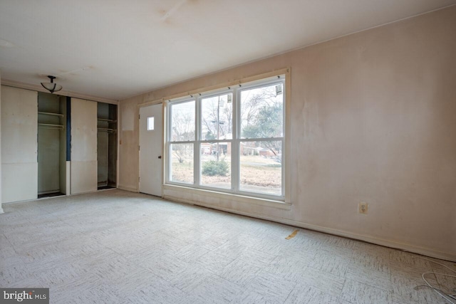 unfurnished room with light floors and baseboards