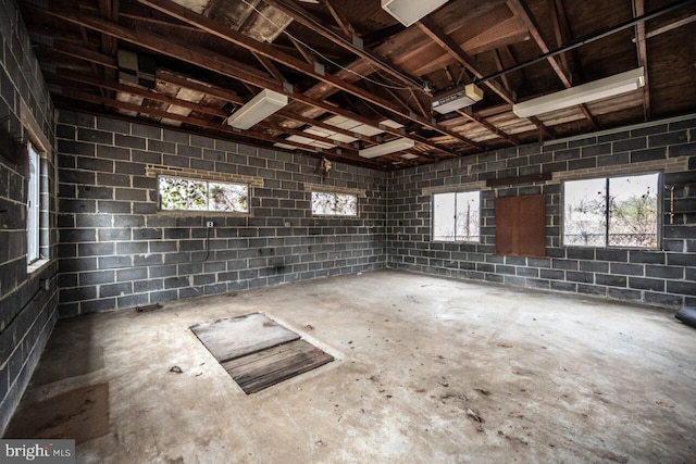 interior space featuring unfinished concrete floors, concrete block wall, and a garage