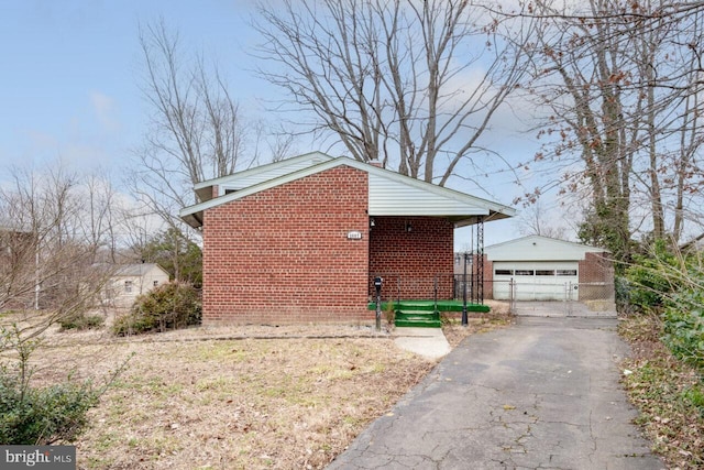 view of property exterior with a gate, fence, an outdoor structure, a detached garage, and brick siding