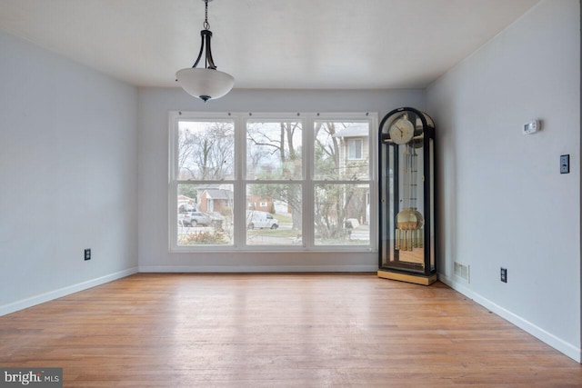 unfurnished dining area with visible vents, baseboards, and wood finished floors