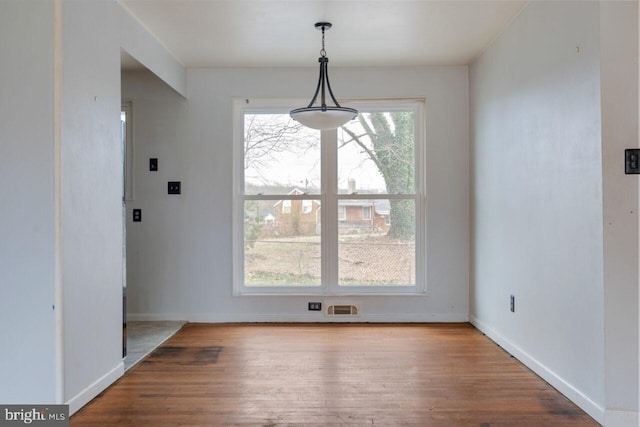 unfurnished dining area with visible vents, baseboards, and wood finished floors